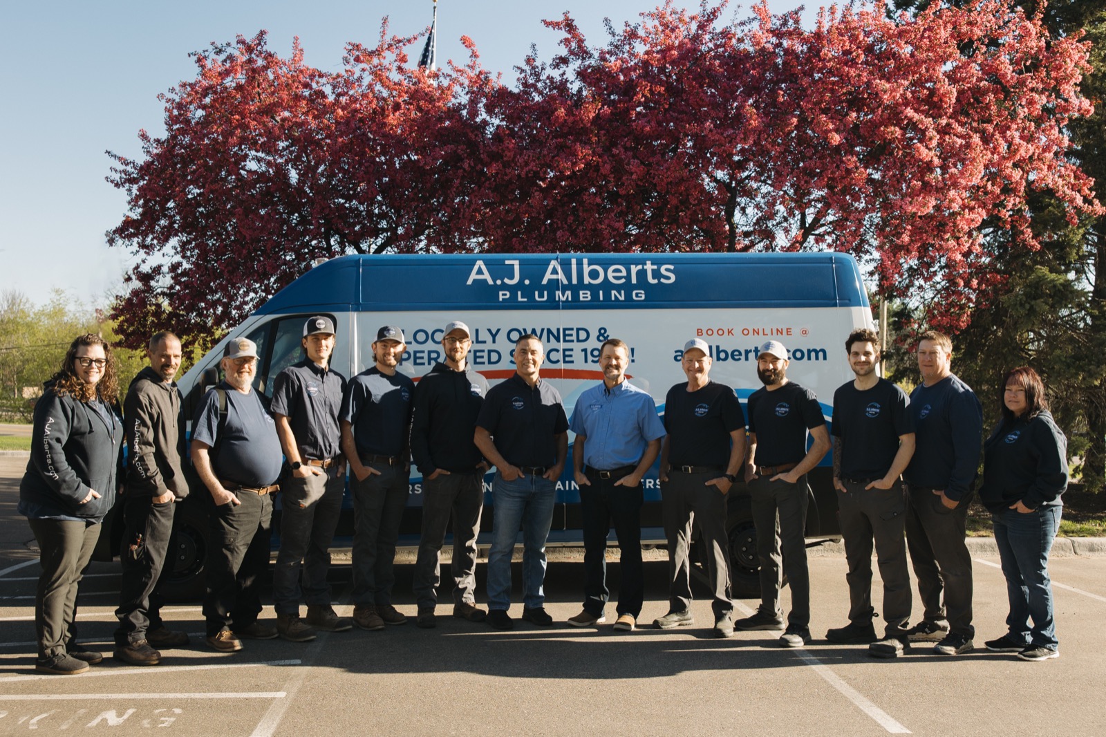 The full A.J. Alberts Plumbing team standing in front of a company service van
